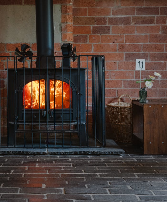 Warm and inviting iron fireplace against a rustic brick wall in an indoor setting.