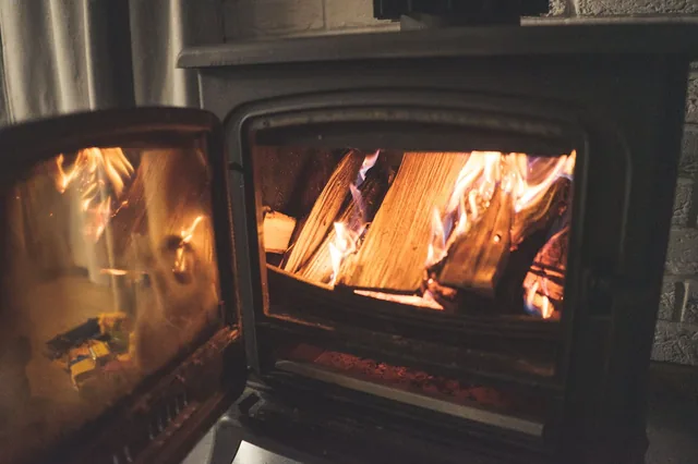 Warm and inviting indoor scene featuring a fireplace with crackling firewood and vivid flames.